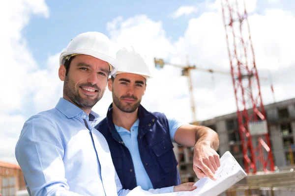 Ingeniero y trabajador viendo el plano en el sitio de construcción — Foto de Stock