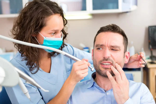 Jovem homem atraente com medo de ser curado por um dentista — Fotografia de Stock
