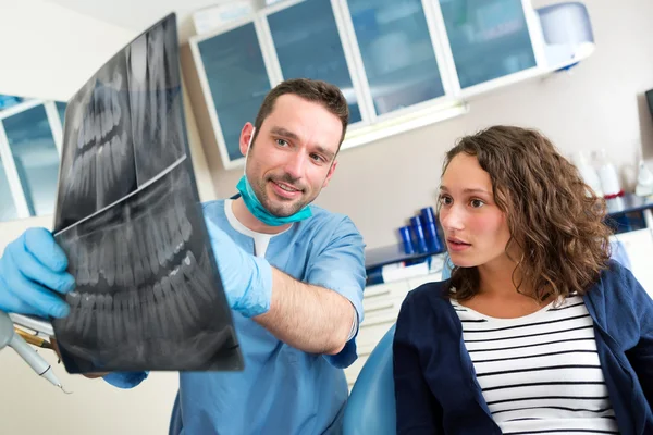 Joven dentista atractivo mostrando rayos X al paciente — Foto de Stock