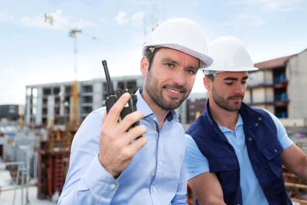 Engineer and worker watching blueprint on construction site — Stock Photo, Image