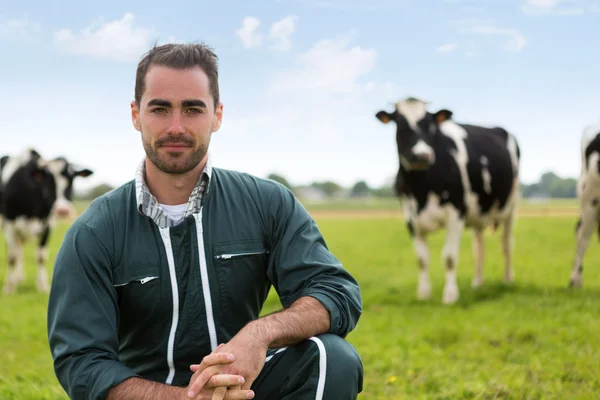 Portrait of a young attractive farmer in a pasture with cows — Stock Photo, Image