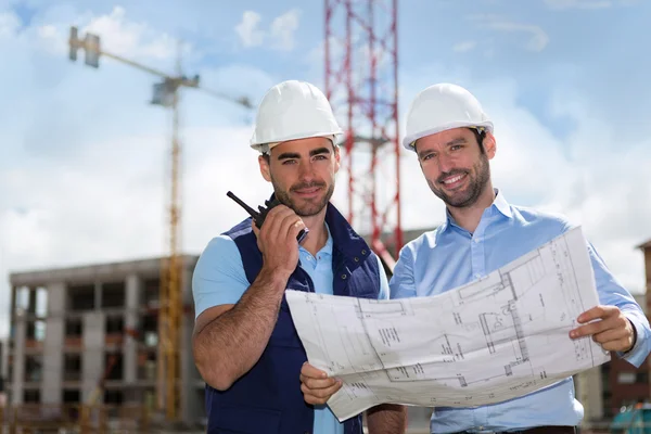 Ingenieur en werknemer kijken blauwdruk op de bouwplaats — Stockfoto