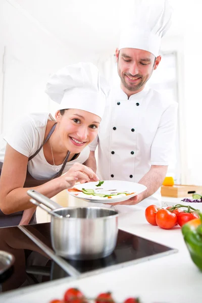 Junger Koch bildet ein junges attraktives Mädchen zum Koch aus — Stockfoto