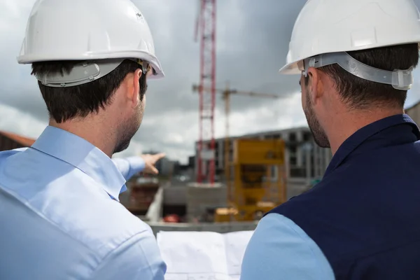 Engineer and worker checking plan on construction site — Stock Photo, Image