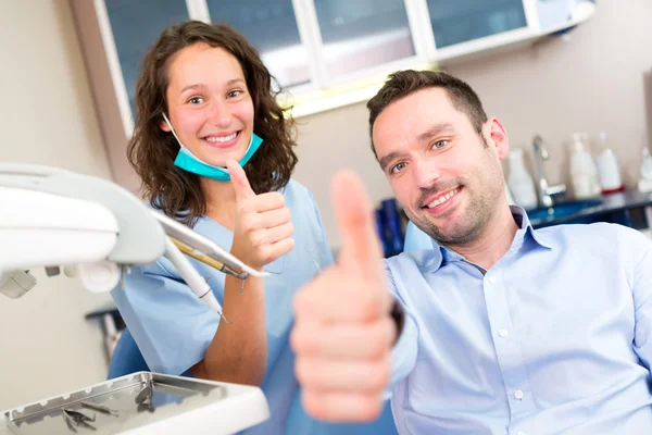 Portret van een jonge aantrekkelijke tandarts in zijn kantoor met patien — Stockfoto