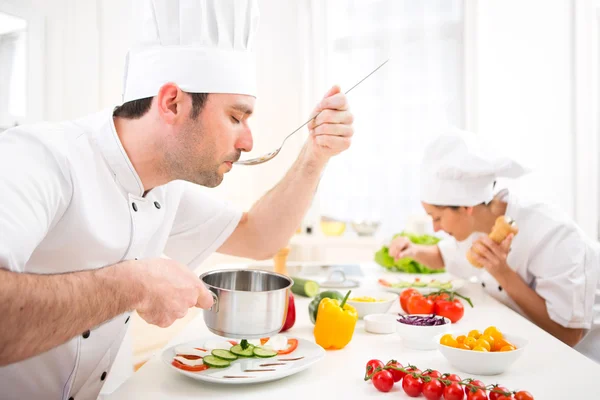 Young attractive professional chef tasting sauce — Stock Photo, Image