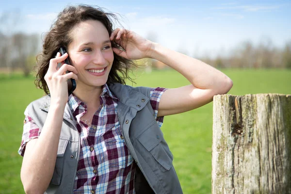 Joven agricultor atractivo en un campo usando teléfono móvil — Foto de Stock