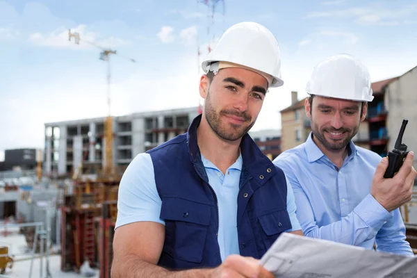 Engineer and worker watching blueprint on construction site — Stock Photo, Image