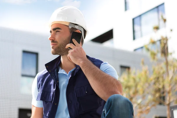 Yong attractive worker using mobile phone  on a construction sit — Stock Photo, Image