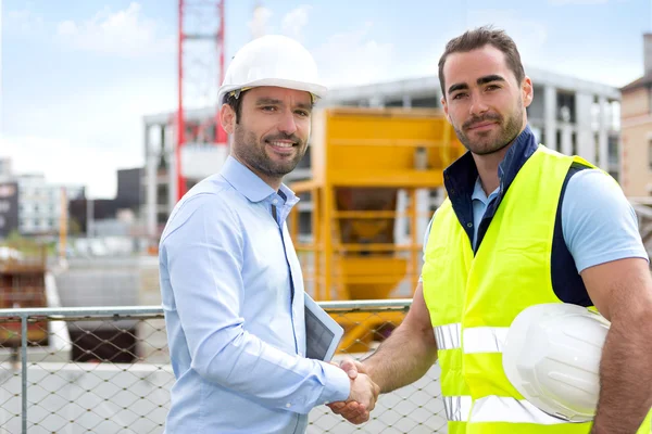 Architekt a pracovníků handshaking na staveništi — Stock fotografie