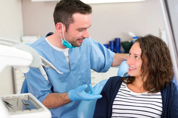 Jovem dentista atraente explicando seu trabalho para um paciente — Fotografia de Stock