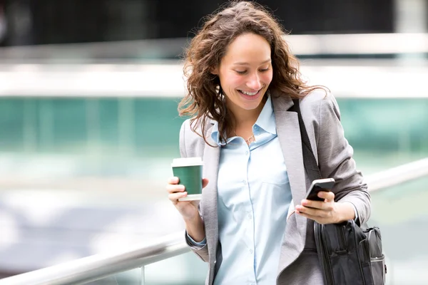 Jonge aantrekkelijke zakenvrouw gebruikend smartphone drinken koffie — Stockfoto