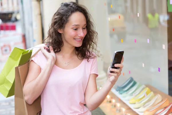 Jonge aantrekkelijke vrouw met behulp van mobiele tijdens het winkelen — Stockfoto