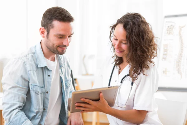 Médico jovem mostrando resultados em comprimido para paciente — Fotografia de Stock