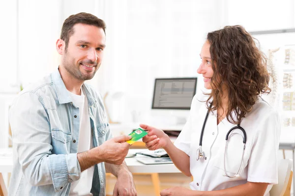 Jeune médecin attrayant prenant carte d'assurance maladie — Photo