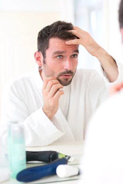 Junger attraktiver Mann kümmert sich um seine Haare — Stockfoto