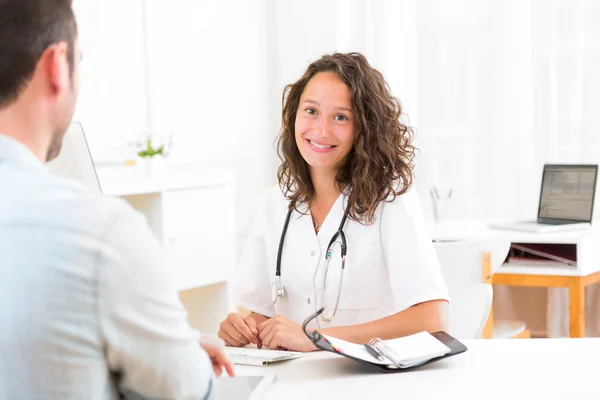 Junger attraktiver Arzt hört seinem Patienten zu — Stockfoto