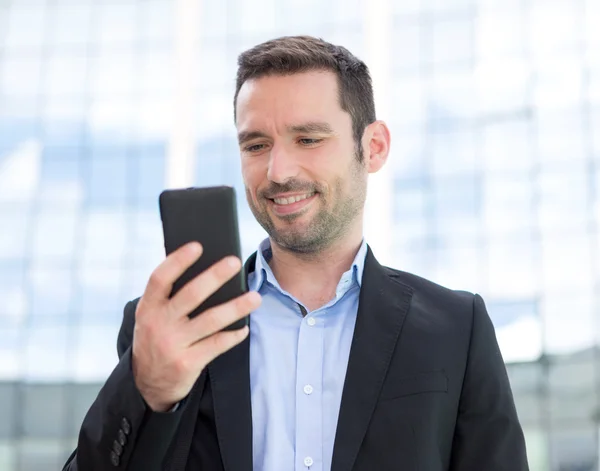 Jonge aantrekkelijke zakenman gebruikend smartphone — Stockfoto