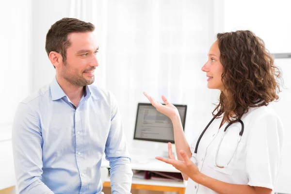 Giovane medico attraente ascoltando il suo paziente — Foto Stock