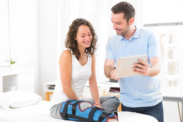 Young attractive physiotherapist using tablet with patient — Stock Photo, Image
