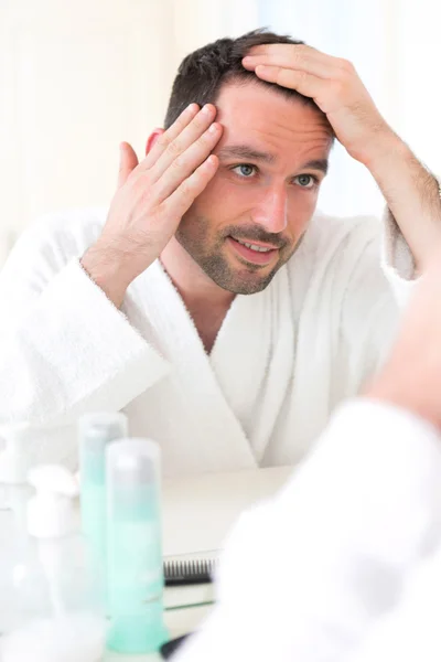 Jovem homem atraente cuidando de seu cabelo — Fotografia de Stock