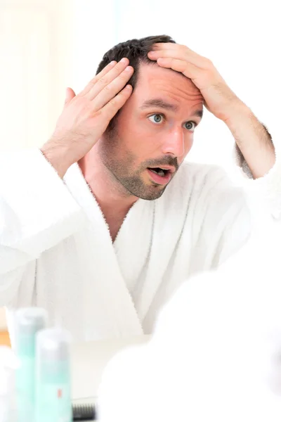 Junger attraktiver Mann kümmert sich um seine Haare — Stockfoto