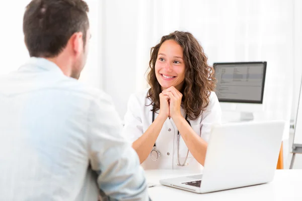 Junger attraktiver Arzt hört seinem Patienten zu — Stockfoto