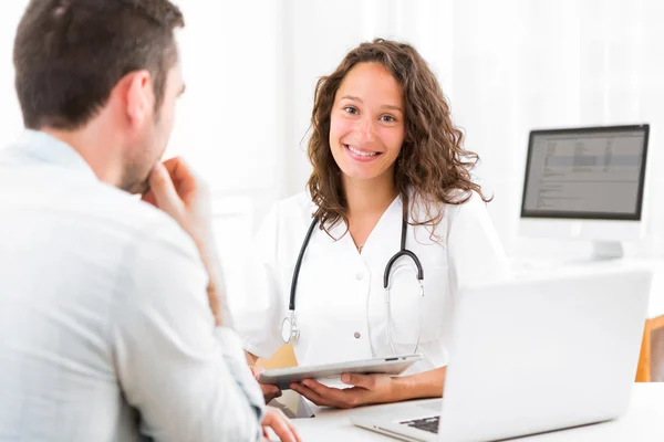 Jonge dokter resultaten op Tablet PC aan patiënt — Stockfoto