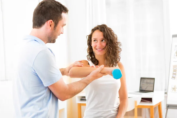 Young attractive woman doing exercise with physiotherapist — Stock Photo, Image