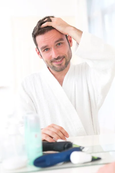 Jovem homem atraente cuidando de seu cabelo — Fotografia de Stock