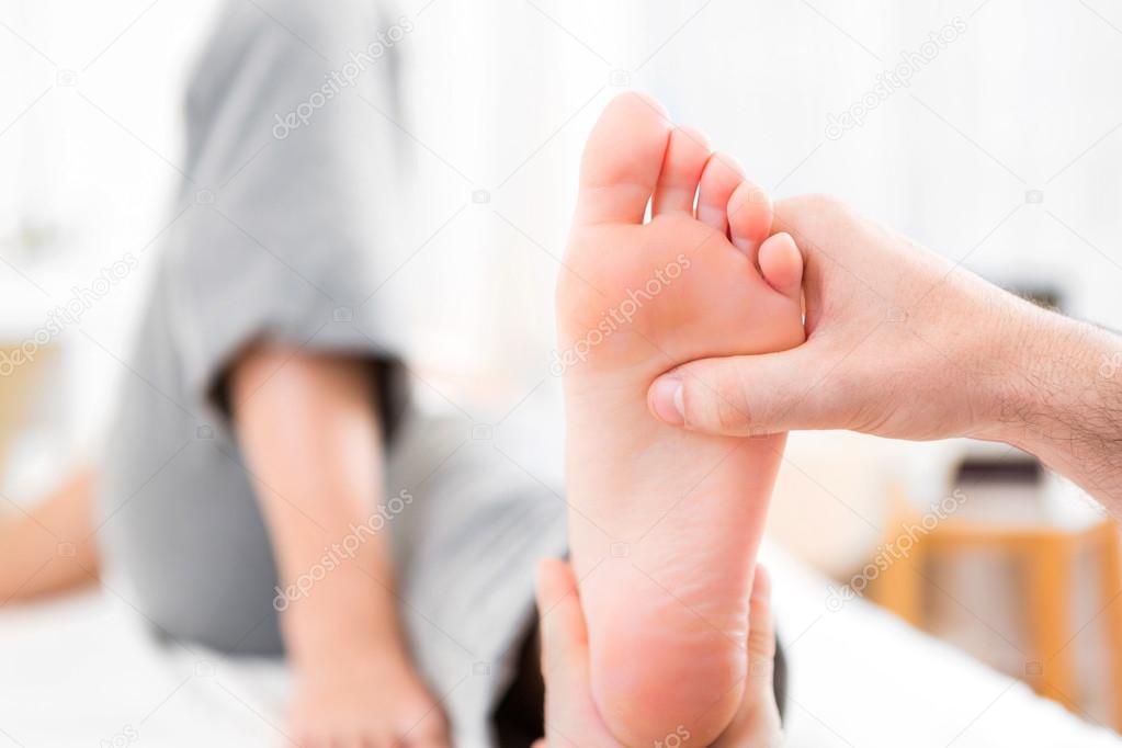 Young attractive physiotherapist doing reflexology on a patient