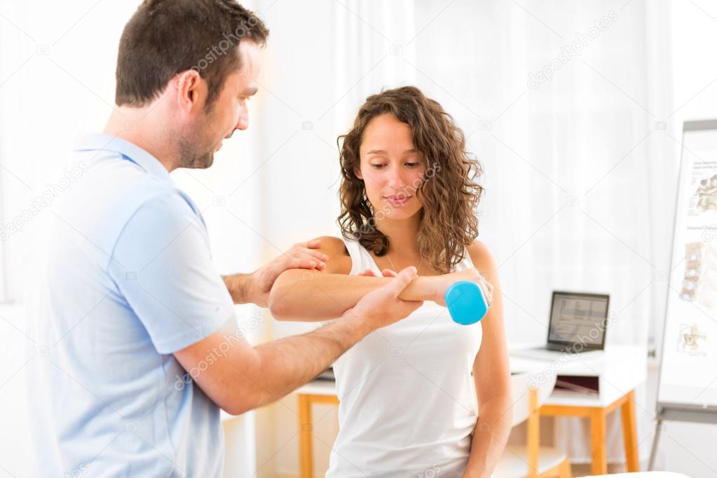 Young attractive woman doing exercise with physiotherapist