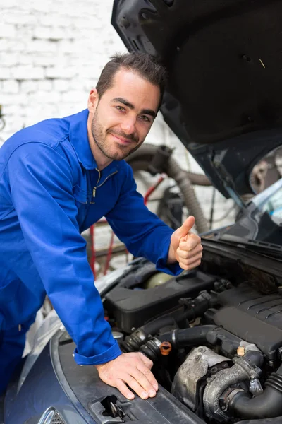 Giovane meccanico attraente che lavora su un'auto in garage — Foto Stock