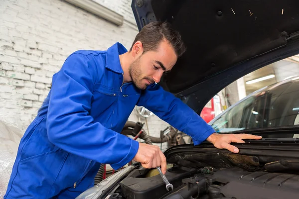 Young attractive mechanic working on a car at the garage — Stock Photo, Image