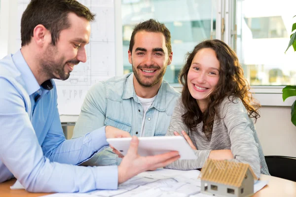 Junge attraktive Leute treffen Immobilienmakler im Büro — Stockfoto