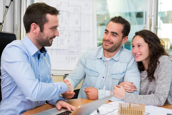 Junge attraktive Leute treffen Immobilienmakler im Büro — Stockfoto