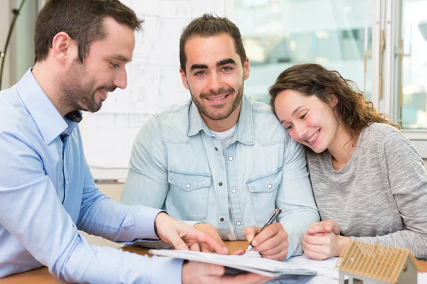 Jeunes gens attrayants signer cotract avec la réunion de l'immobilier — Photo