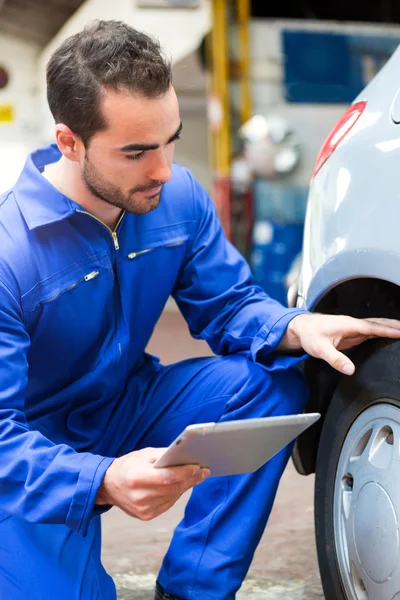 Young attractive mechanic working on a car at the garage — Stock Photo, Image