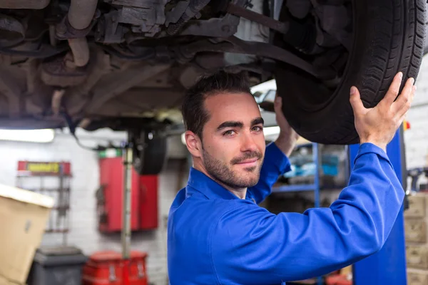 Joven mecánico atractivo trabajando en un coche en el garaje — Foto de Stock