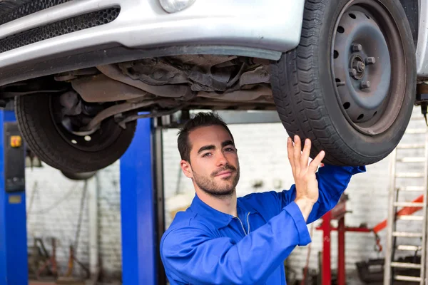 Young attractive mechanic working on a car at the garage — Stock Photo, Image