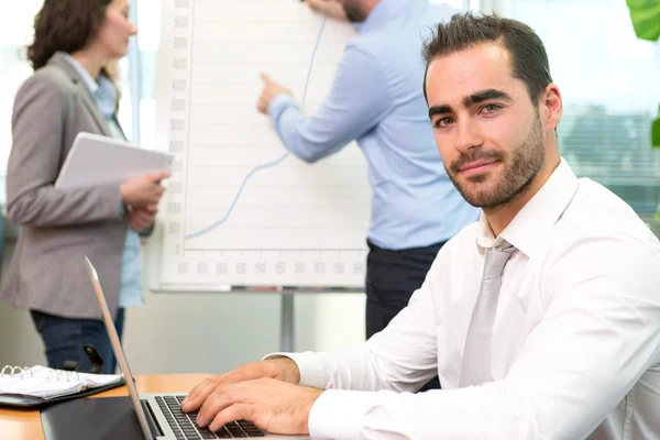 Young attractive businessman working at the office with associat — Stock Photo, Image