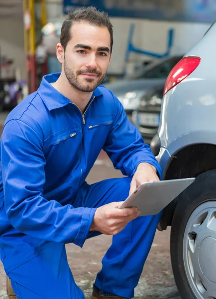 Joven mecánico atractivo trabajando en un coche en el garaje — Foto de Stock