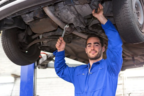 Joven mecánico atractivo trabajando en un coche en el garaje — Foto de Stock