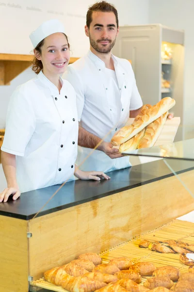 Young attractive bakers working at the bakery — Stock Photo, Image