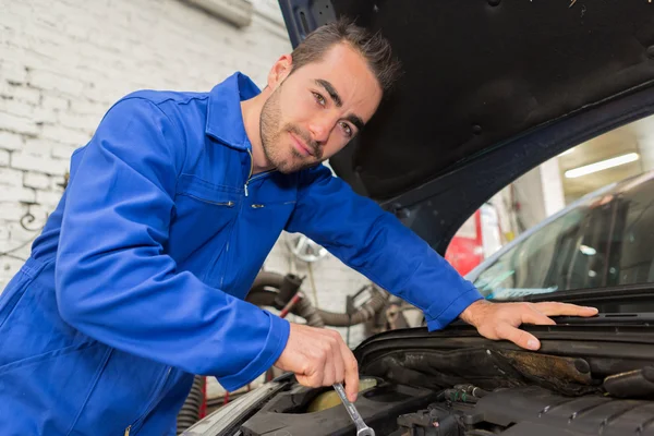 Joven mecánico atractivo trabajando en un coche en el garaje — Foto de Stock