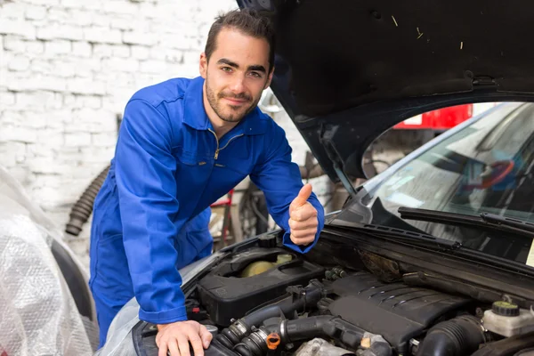 Jovem mecânico atraente trabalhando em um carro na garagem — Fotografia de Stock