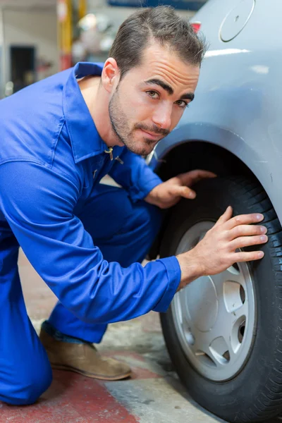 Jovem mecânico atraente trabalhando em um carro na garagem — Fotografia de Stock