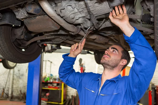 Joven mecánico atractivo trabajando en un coche en el garaje — Foto de Stock