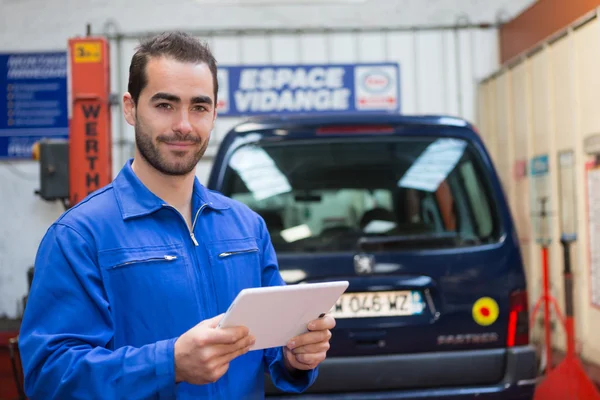 Jovem mecânico atraente trabalhando na garagem — Fotografia de Stock