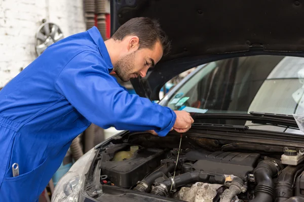 Giovane meccanico attraente che lavora su un'auto in garage — Foto Stock